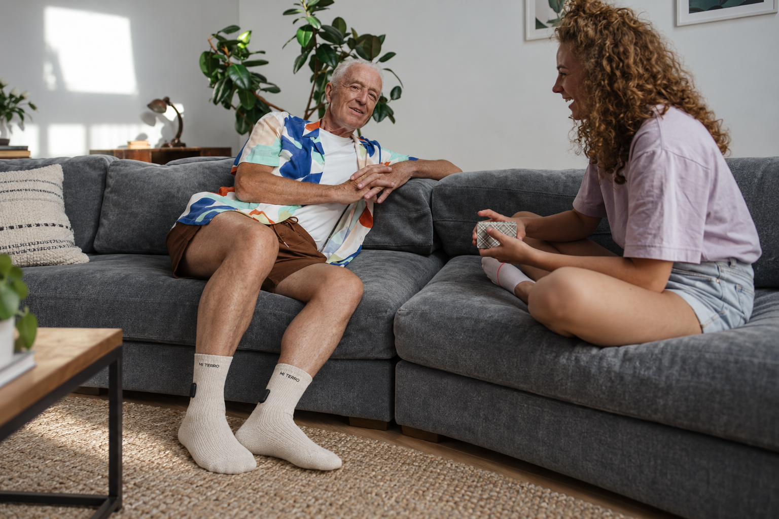 Older man relaxing at home with a family member, wearing a visualization of cream Mi Terro socks with sealed ankle modules