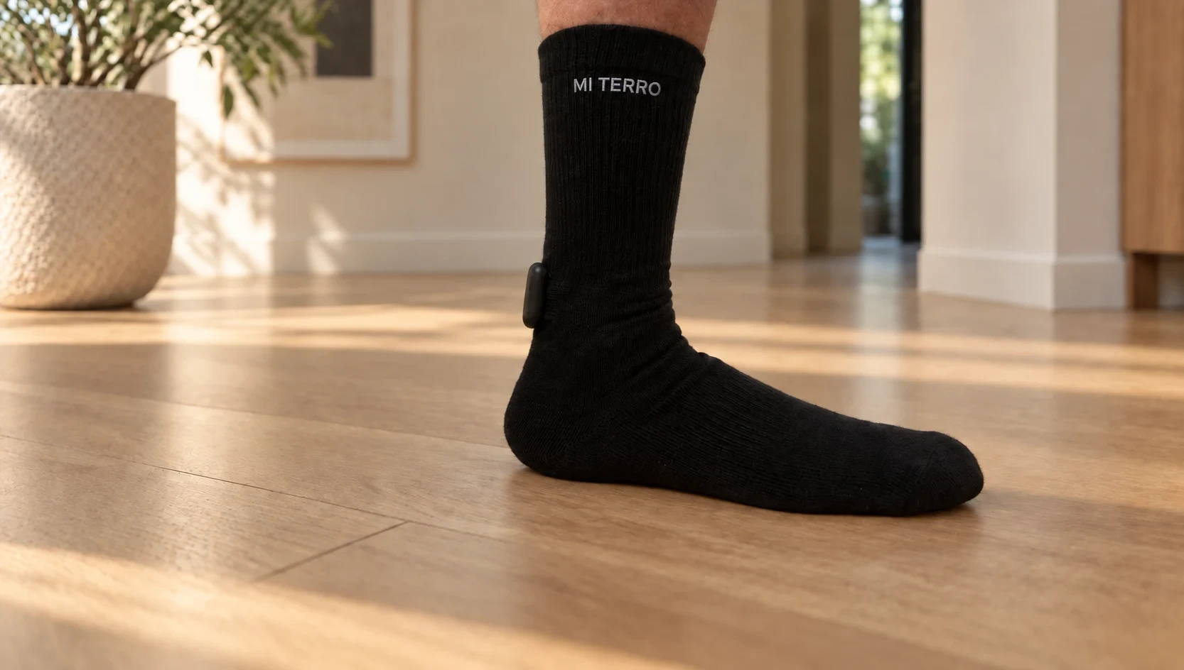 Mi Terro Smart Sock worn on a foot, with the removable ankle module and logo visible